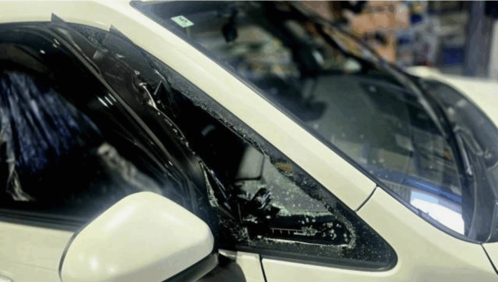 粉々に割れたフロントガラスと飛散したガラス片の清掃作業